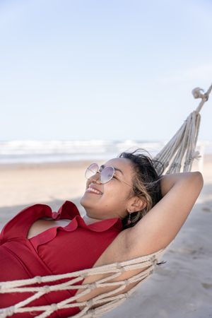 A young Hispanic woman sleeping peacefully on a hammock with an open mouth at the beach