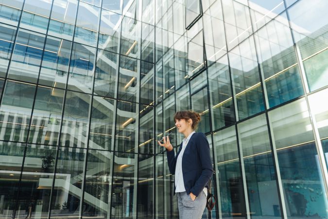 Smiling entrepreneur browsing smartphone outside office building