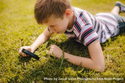 Boy exploring garden grass with his magnifier 493zL0