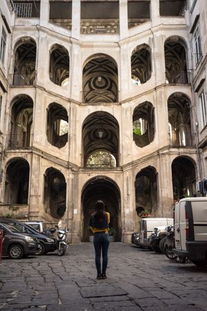 Faceless female on vacation looking at ancient impressive palace