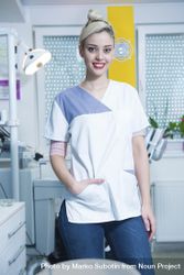 Happy female dentist in office with hand in pocket 0P9Xm5