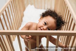 Cute baby boy standing up and leaning in his crib 5R6RO5