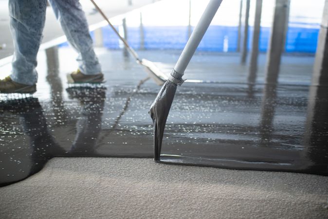 Crop unrecognizable people pouring concrete on floor