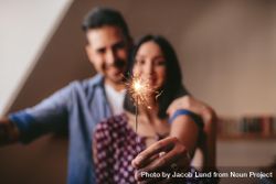 Young couple celebrating with sparkler indoors 5z2aX5