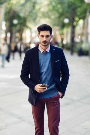 Attractive man in the street wearing elegant suit with smart phone in his hand