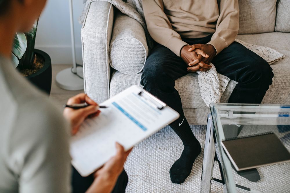 Back view of therapist writing on a note while listening to a patient