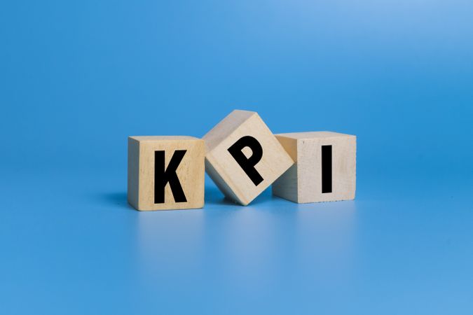KPI letter symbol on wooden blocks isolated on blue background. concept of business key performance indicator