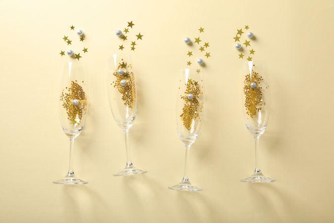 Champagne glasses with glitter on beige background, space for text