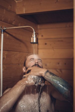 Man taking shower in wooden bathroom