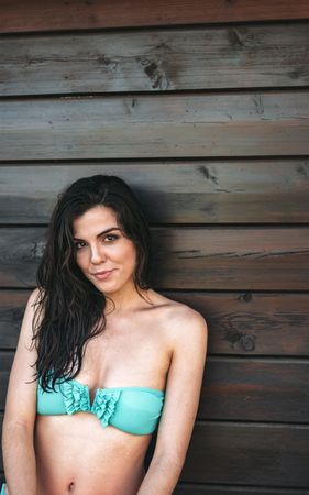 Young woman posing by wooden wall