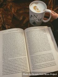 Cup of coffee beside an open book 0yMN10