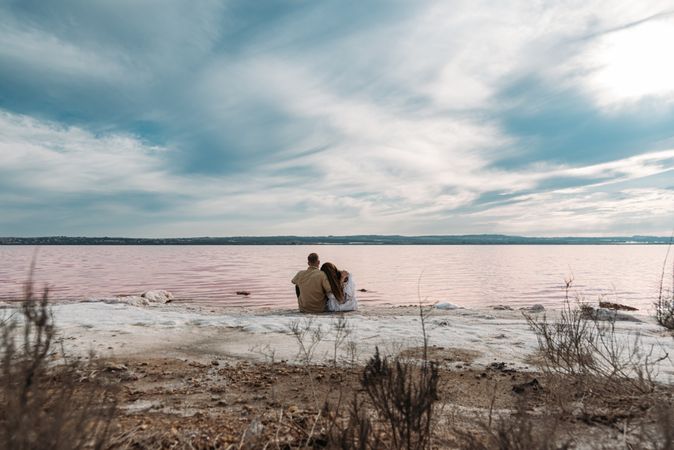 adorable couple sitting on an amazing beach with pink water