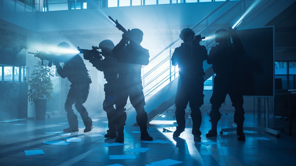 Masked Fireteam of Armed SWAT Police Officers Storm a Dark Seized Office Building with Desks and Computers.