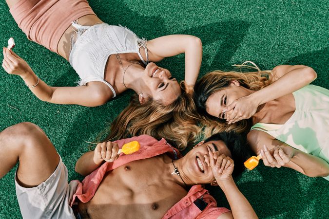 a group of young people having a good time and eating ice-cream lying on grass