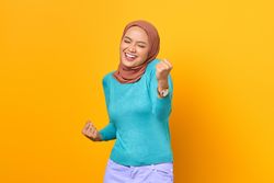 Thrilled Muslim woman celebrating with eyes closed