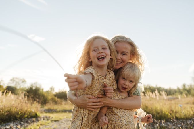 Cheerful mother embracing daughters in countryside