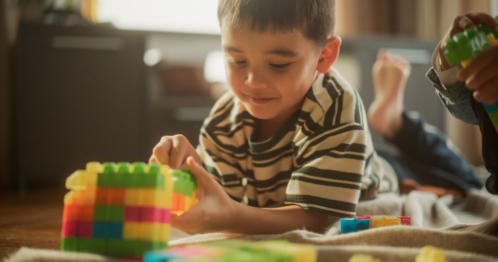 Portrait of Cute Male Asian Child Playing with Colourful Building Blocks in his Room During the Day.