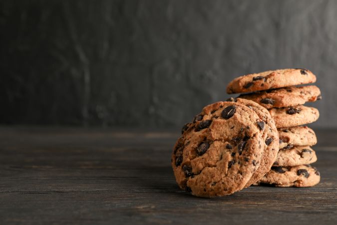 Stack of tasty chocolate chip cookies on wooden background. Space for text