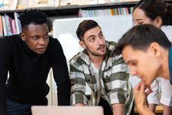 Diverse colleagues leaning over desk working on project