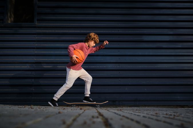 Little basketball player riding skateboard