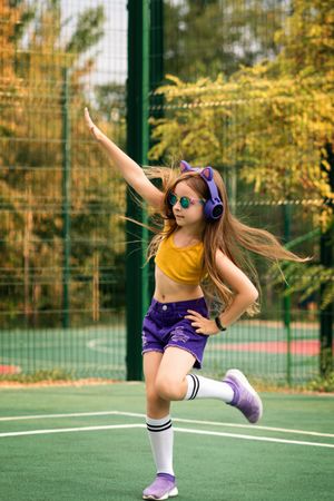 Schoolgirl freely dancing on sports ground