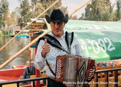 Mexican man in hat playing accordion on riverside bGY8a5