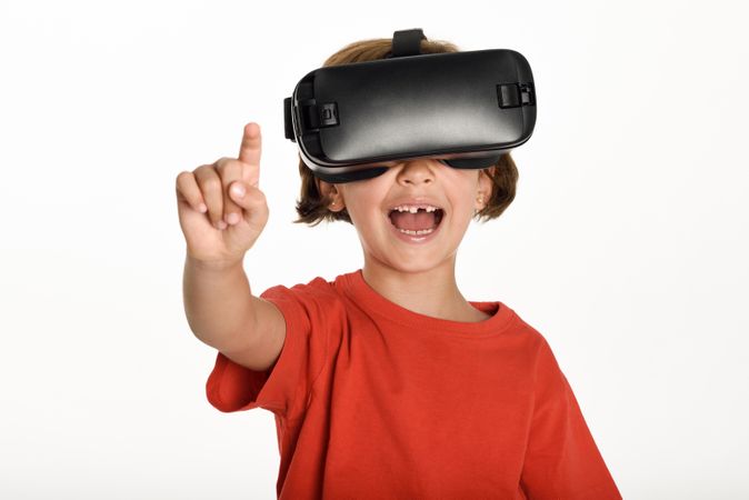 Happy girl looking in VR glasses and gesturing with finger pointing up