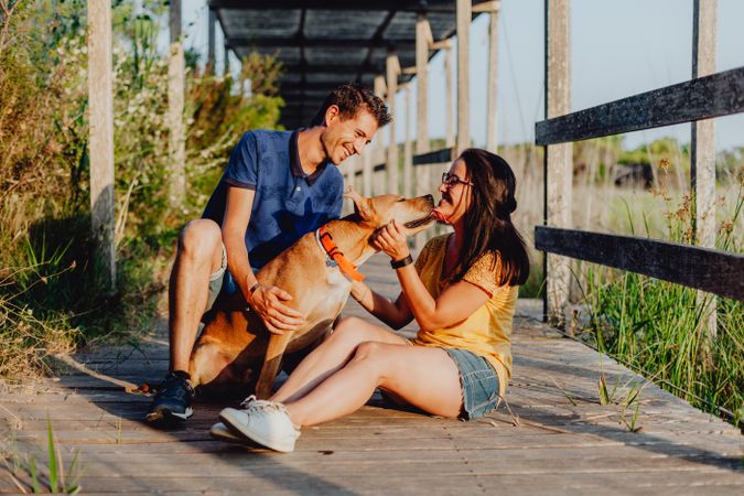 Happy adult couple having fun with dog at countryside