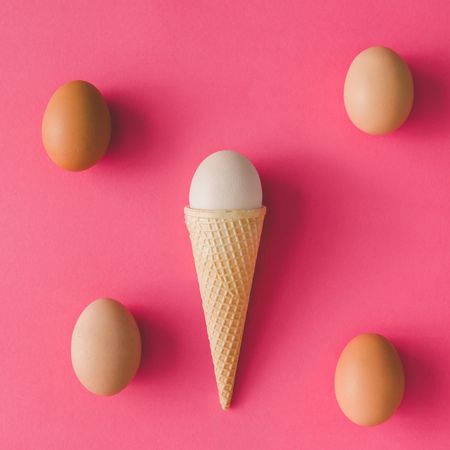 Ice cream cone with egg on pink background