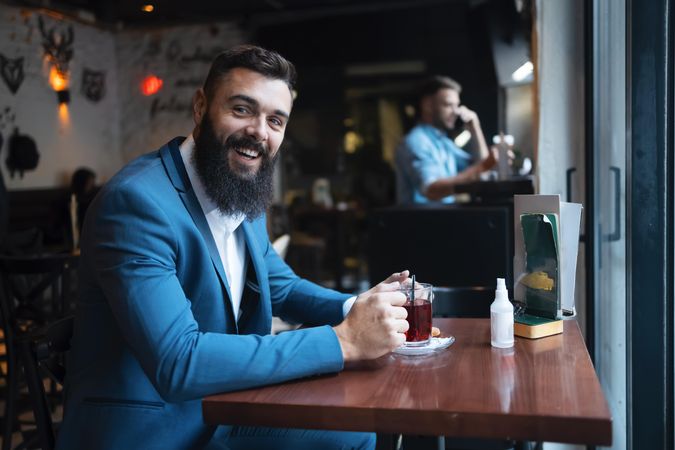 Man smiling with tea in a cafe