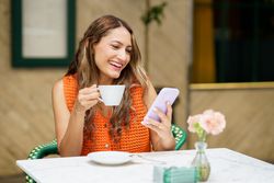 Latina woman smiling while using mobile phone in a cafeteria