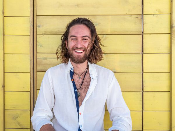Cheerful guy sitting near blue wall