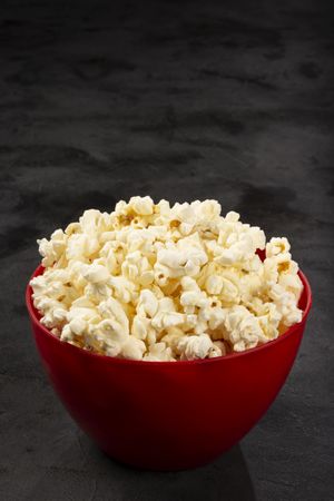 Bowl with salted popcorn sore the table.