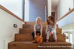 Little kids sitting on stairway, with boy grabbing a teddy bear bYPJ14