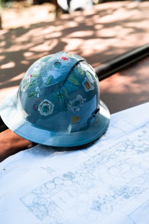 Hard hat decorated with stickers sitting on blue print