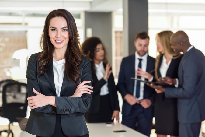Female business leader standing in foreground of busy office