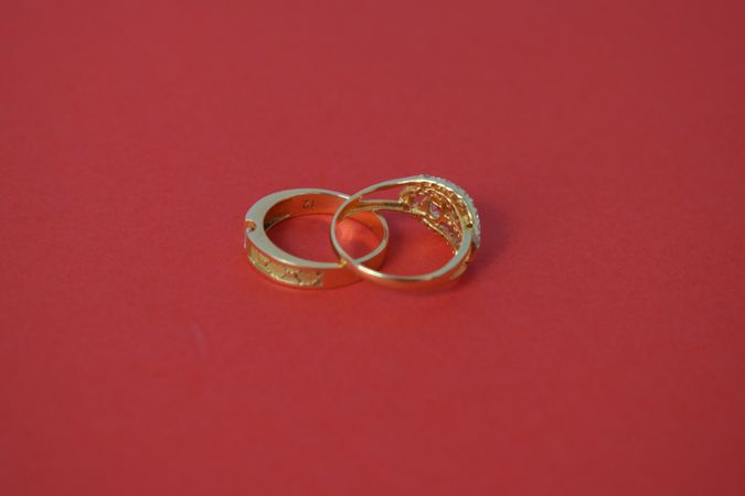Two gold wedding rings together on red table