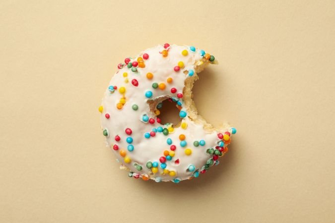 Tasty bitten donut on beige background, top view