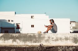 Young male sitting with smartphone and headphones