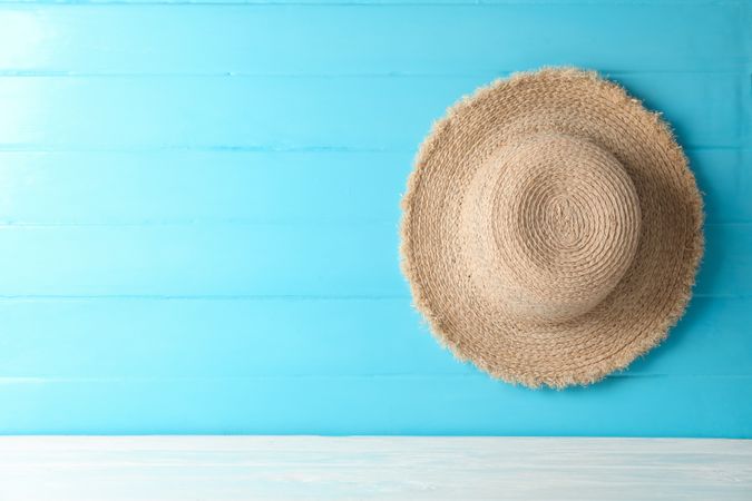Straw hat on table against color background, space for text. Summer vacation backdrop