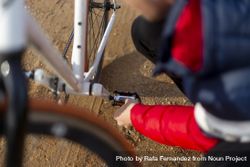 Man repairing his bicycle outdoors on dirt road 4mWZmW