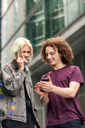Girlfriend and boyfriend looking down at cell phones walking on British city street