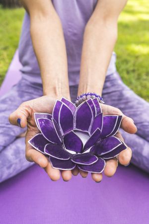 Close up of woman's hands offering a purple glass lotus. Yoga and meditation concept.