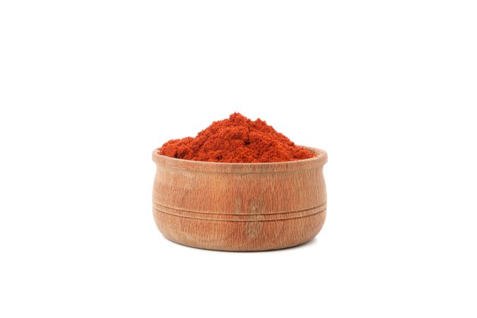 Side view of wooden bowl full of red pepper powder