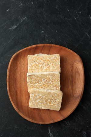 Top view slices of fresh tempeh on wooden plate