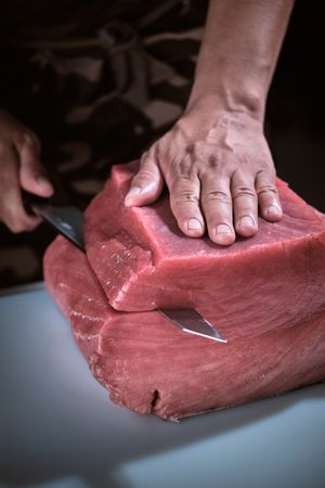 Male hands of a chef cutting a delicious loin of fresh bluefin t