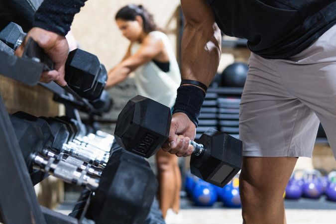 Anonymous sportsman near dumbbells weight set