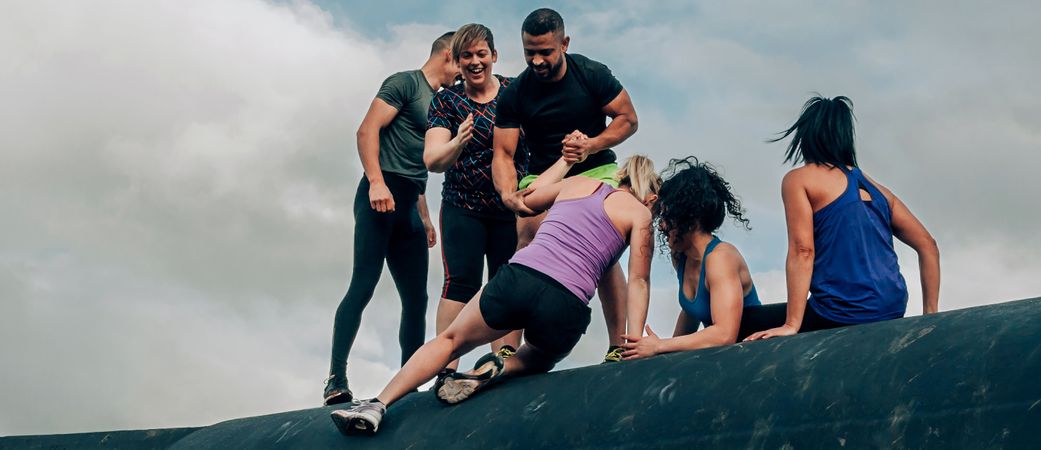 Participants in obstacle course climbing a drum