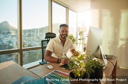 Attractive male designer sitting at his desk and smiling bG7PVb