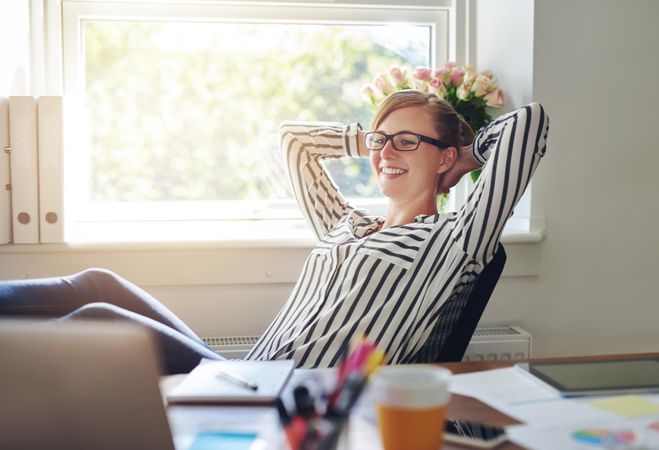 Happy female entrepreneur leaning back and relaxing while working from home office